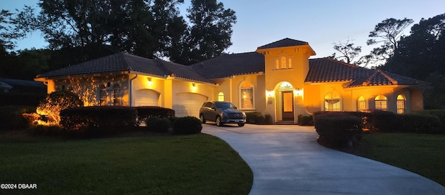 mediterranean / spanish house featuring a garage and a lawn