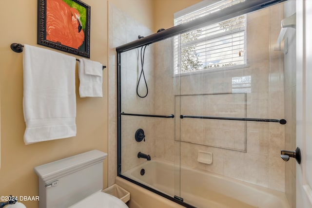 bathroom featuring bath / shower combo with glass door and toilet