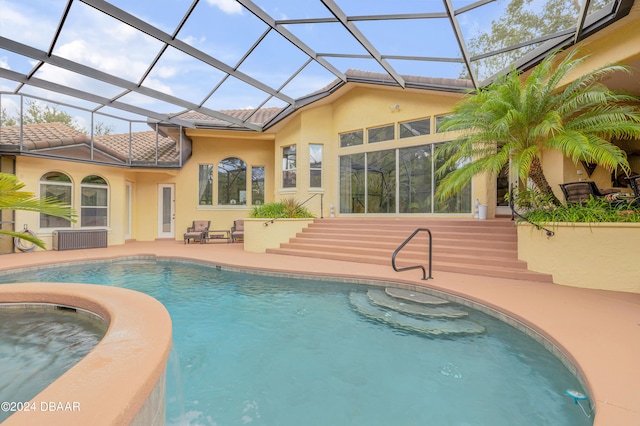 view of swimming pool featuring glass enclosure, a patio, and an in ground hot tub