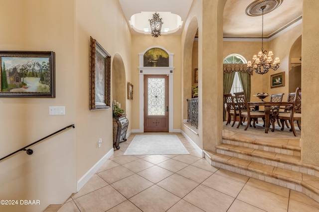 tiled entrance foyer with ornamental molding, a towering ceiling, and a notable chandelier