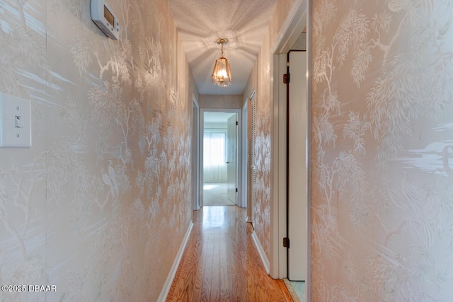 130 Kimberly Dr, Ormond Beach, FL 32174 - hall with light wood-style floors, baseboards, wallpapered walls, and a chandelier