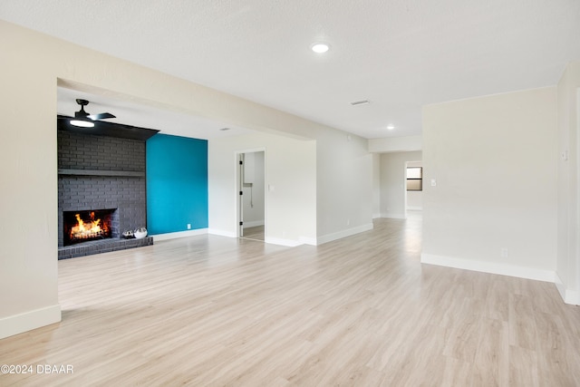 1512 Old Kings Rd, Daytona Beach, FL 32117 - unfurnished living room with ceiling fan, a fireplace, light hardwood / wood-style floors, and a textured ceiling