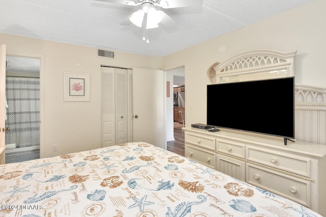 bedroom featuring a closet, ensuite bath, a textured ceiling, dark hardwood / wood-style floors, and ceiling fan