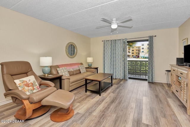 living room with ceiling fan, a textured ceiling, and light wood-type flooring