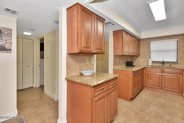 kitchen featuring tasteful backsplash, light stone countertops, and sink