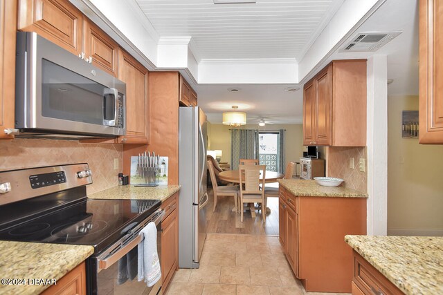 kitchen featuring light stone counters, appliances with stainless steel finishes, ceiling fan, light hardwood / wood-style flooring, and crown molding