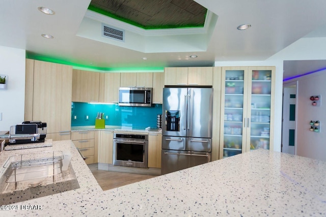 241 Riverside Dr Unit 402, Daytona Beach, FL 32117 - kitchen featuring stainless steel appliances, light brown cabinets, a tray ceiling, recessed lighting, and light stone countertops