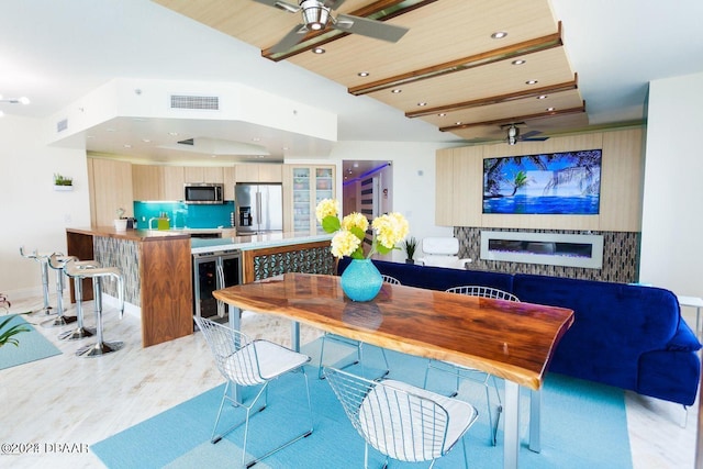 dining room with beverage cooler, wooden ceiling, ceiling fan, a raised ceiling, and light hardwood / wood-style flooring