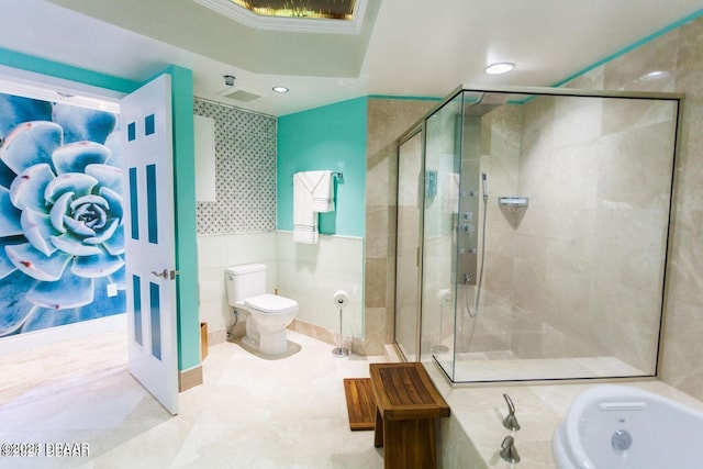 bathroom featuring toilet, independent shower and bath, and tile walls