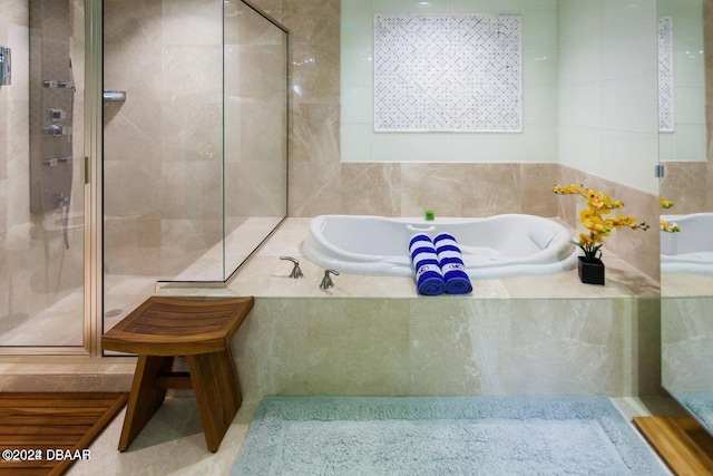 bathroom with tile walls and independent shower and bath