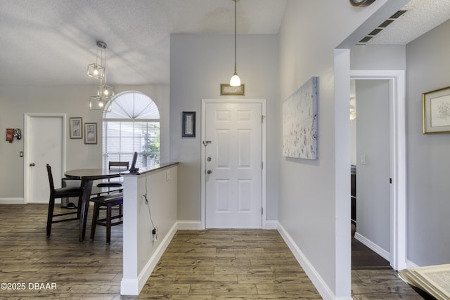 entrance foyer featuring baseboards, visible vents, dark wood-type flooring, and a textured ceiling