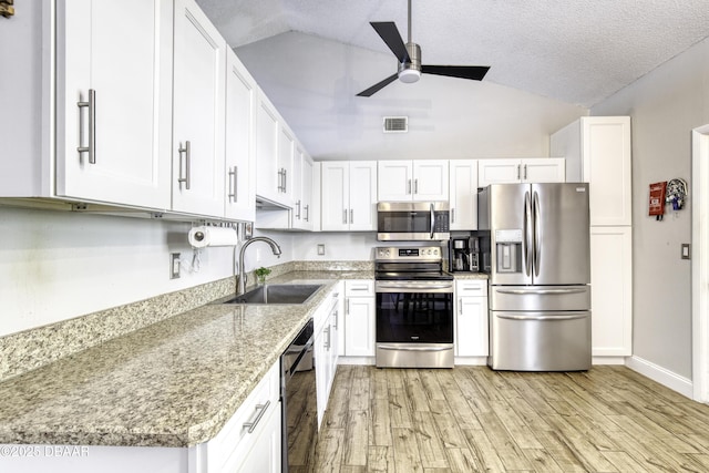 kitchen featuring vaulted ceiling, a sink, a ceiling fan, light wood-type flooring, and stainless steel appliances
