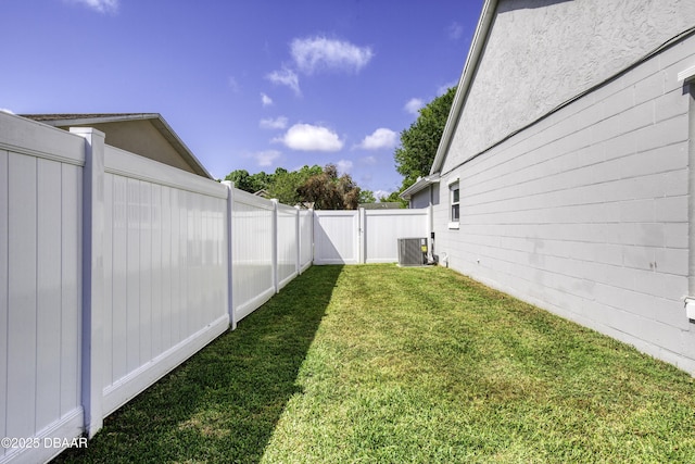 view of yard with a fenced backyard, a gate, and central AC unit