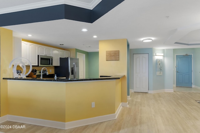 kitchen with light wood finished floors, baseboards, white cabinets, appliances with stainless steel finishes, and a peninsula