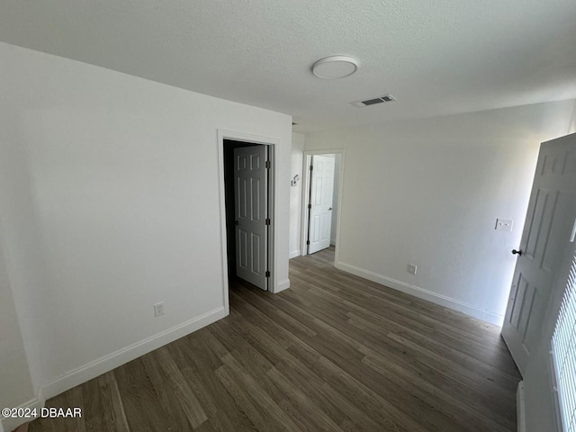 empty room featuring a textured ceiling and dark wood-type flooring