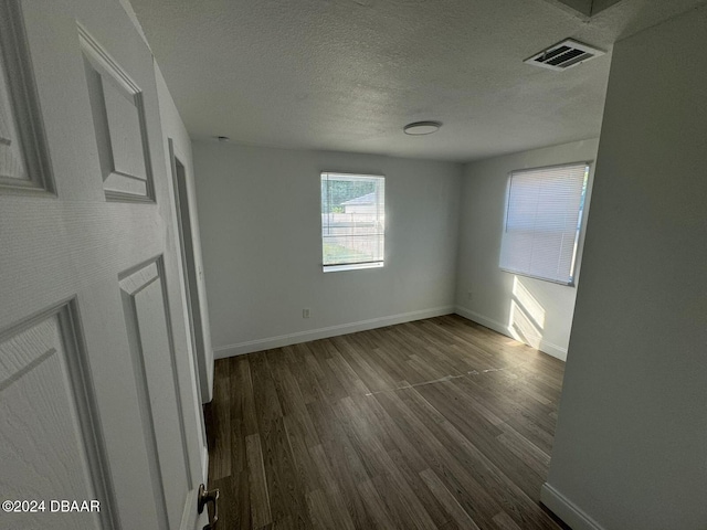 spare room with a textured ceiling and dark wood-type flooring