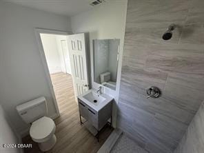 bathroom with wood-type flooring, vanity, toilet, and walk in shower