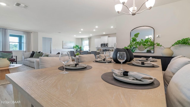 dining area with light hardwood / wood-style flooring and a notable chandelier