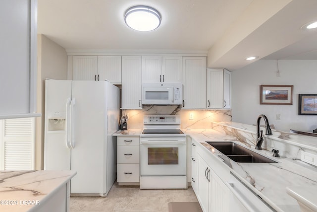 kitchen with white appliances, a sink, light stone countertops, decorative backsplash, and white cabinets
