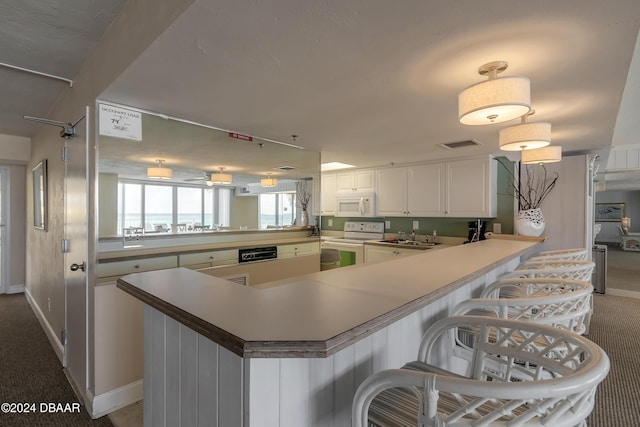 kitchen featuring white appliances, a peninsula, carpet flooring, a sink, and baseboards
