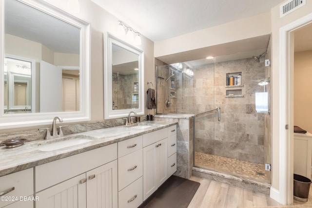 bathroom with a stall shower, wood finished floors, and double vanity