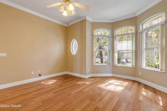 empty room featuring ornamental molding, light wood-type flooring, a healthy amount of sunlight, and ceiling fan