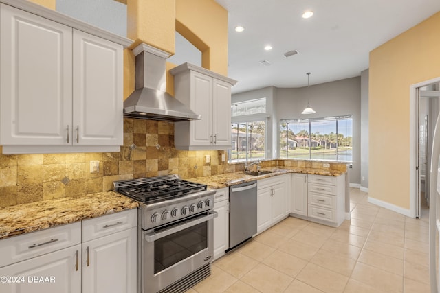 kitchen with white cabinets, sink, tasteful backsplash, wall chimney range hood, and appliances with stainless steel finishes