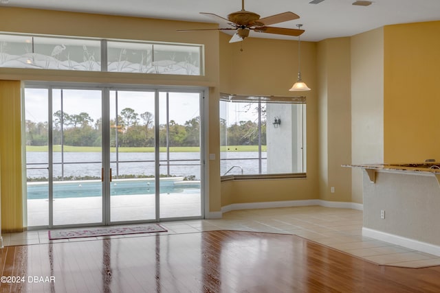 doorway to outside with light hardwood / wood-style flooring, a water view, a healthy amount of sunlight, and ceiling fan