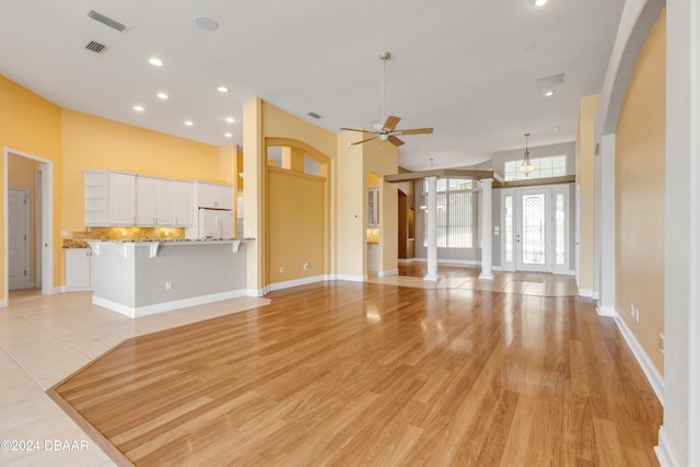 unfurnished living room with light hardwood / wood-style flooring, ceiling fan, and decorative columns