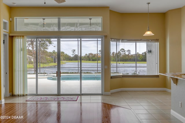 doorway featuring hardwood / wood-style floors, ceiling fan, a healthy amount of sunlight, and a water view