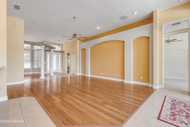 unfurnished living room with ornate columns, light wood-type flooring, and ceiling fan