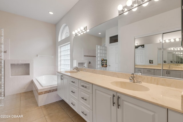 bathroom featuring tile patterned flooring, vanity, and tiled tub