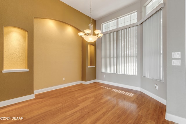 unfurnished room with wood-type flooring and a notable chandelier