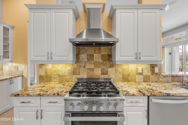 kitchen with white cabinets, stainless steel appliances, wall chimney exhaust hood, and tasteful backsplash