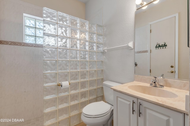 bathroom with toilet, vanity, and a tile shower