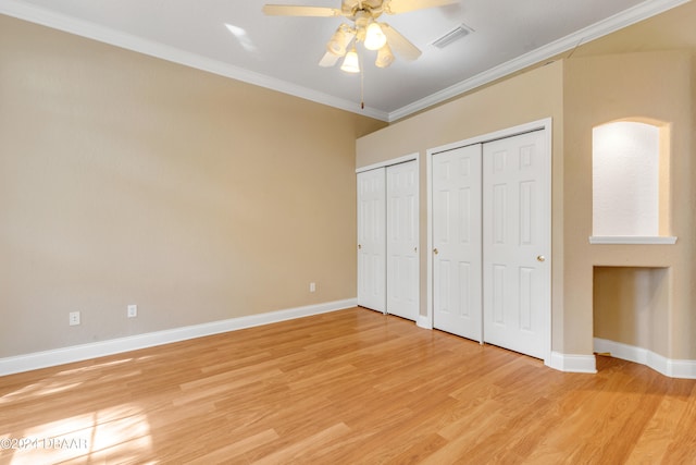 unfurnished bedroom with multiple closets, crown molding, ceiling fan, and light hardwood / wood-style flooring