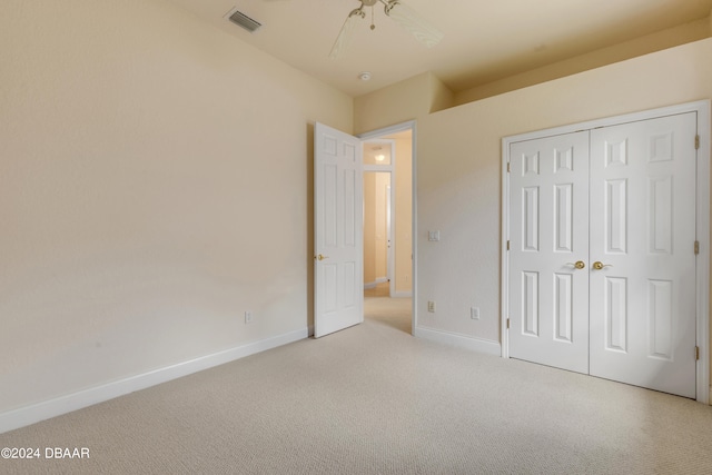 unfurnished bedroom featuring ceiling fan, light carpet, and a closet