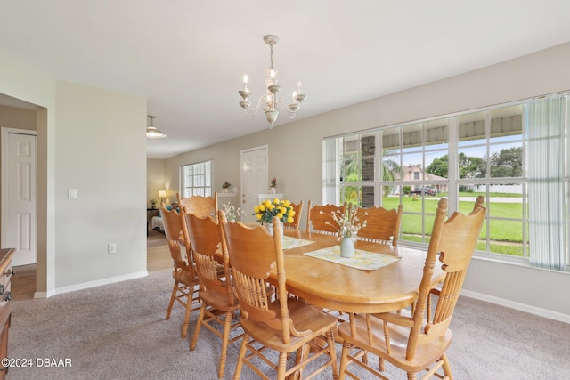 dining space with light colored carpet, a healthy amount of sunlight, and a chandelier