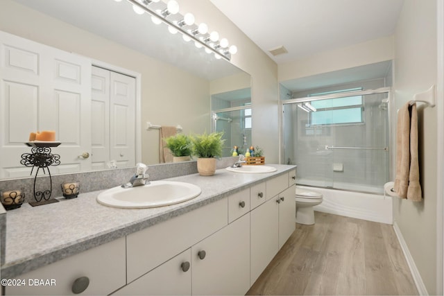 full bathroom with shower / bath combination with glass door, wood-type flooring, toilet, and vanity