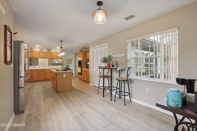 kitchen with pendant lighting, light hardwood / wood-style floors, a center island, and stainless steel fridge