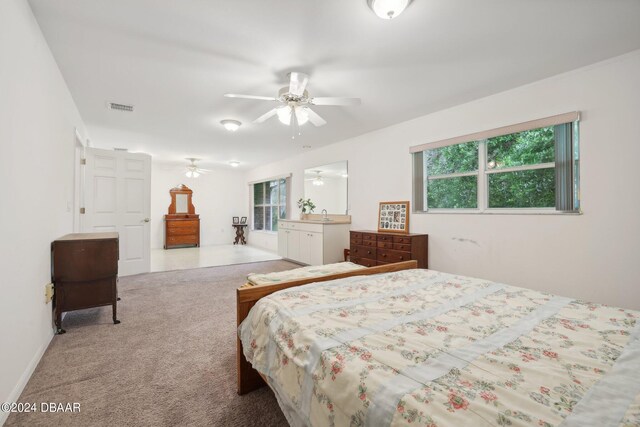 bedroom with multiple windows, light colored carpet, and ceiling fan