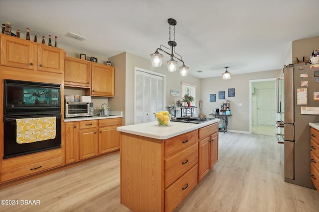 kitchen with stainless steel appliances, light hardwood / wood-style floors, sink, a kitchen island, and decorative light fixtures