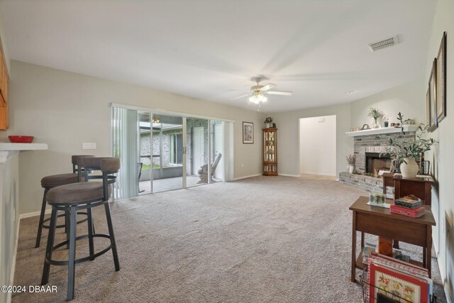 carpeted living room featuring a fireplace and ceiling fan