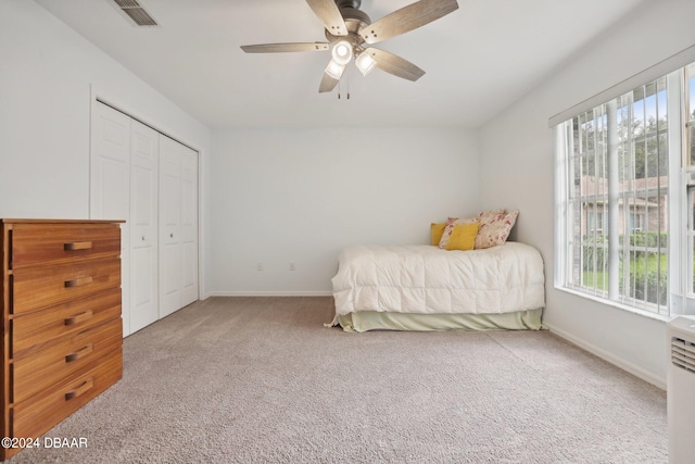 carpeted bedroom featuring multiple windows, ceiling fan, and a closet