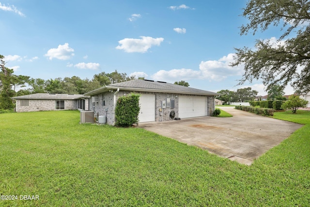 back of property with central air condition unit, a garage, and a yard