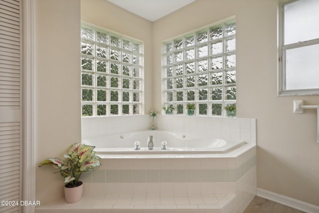 bathroom featuring tiled bath and a wealth of natural light