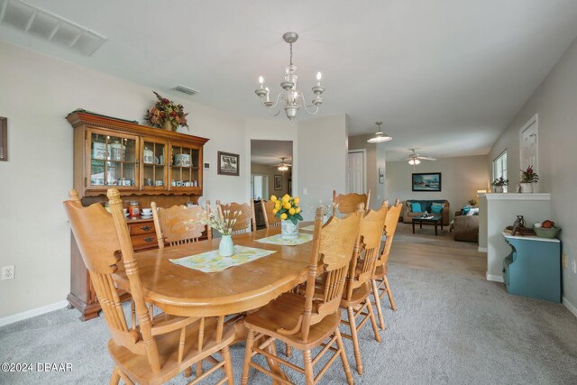 dining room featuring light carpet and ceiling fan with notable chandelier