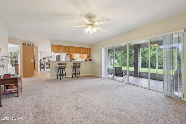 unfurnished living room featuring ceiling fan and light carpet