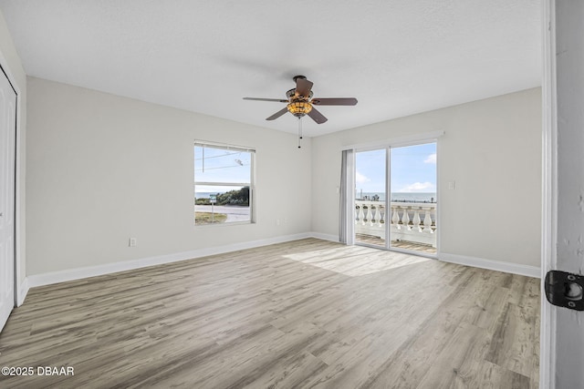 interior space with baseboards, ceiling fan, light wood finished floors, and plenty of natural light