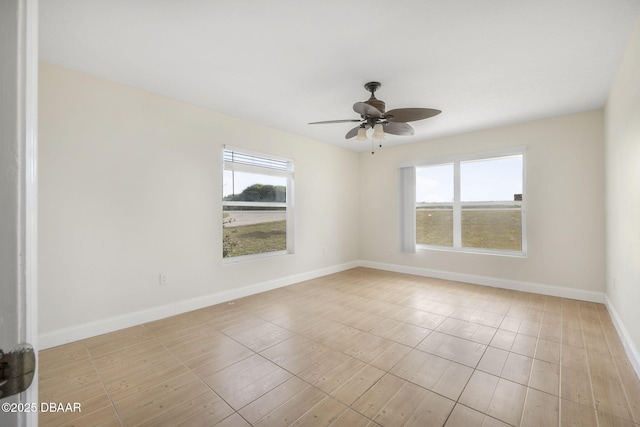 spare room featuring ceiling fan, baseboards, and plenty of natural light